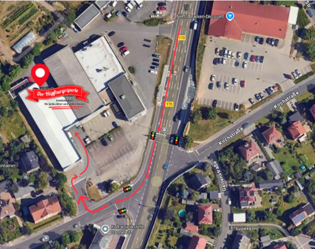 Luftaufnahme eines Unternehmens mit einer roten Stecknadel, die Wegbeschreibungen mit Ampeln und Straßen zeigt.