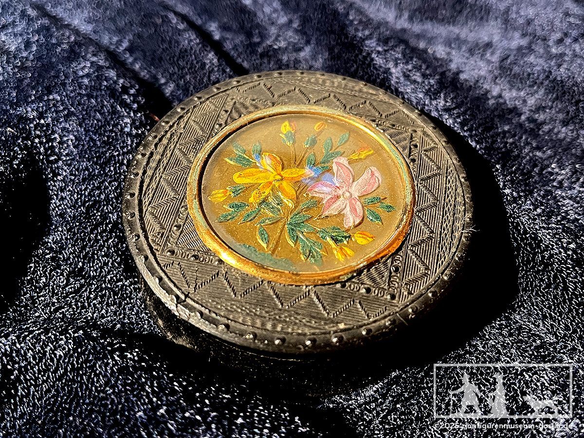 Fein geschnitzter Deckel einer Pillendose mit floralem Muster.