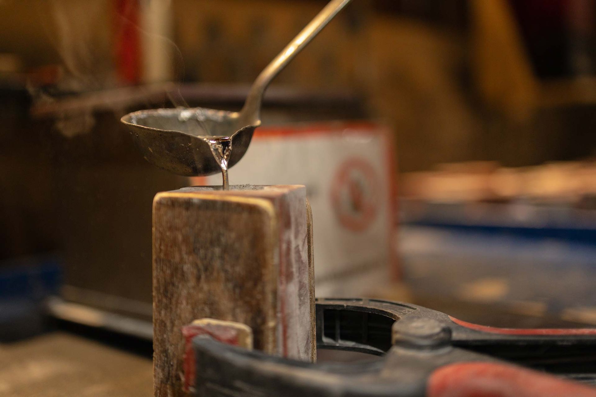 Eine Person gießt Flüssigkeit aus einem Löffel in ein Stück Holz.