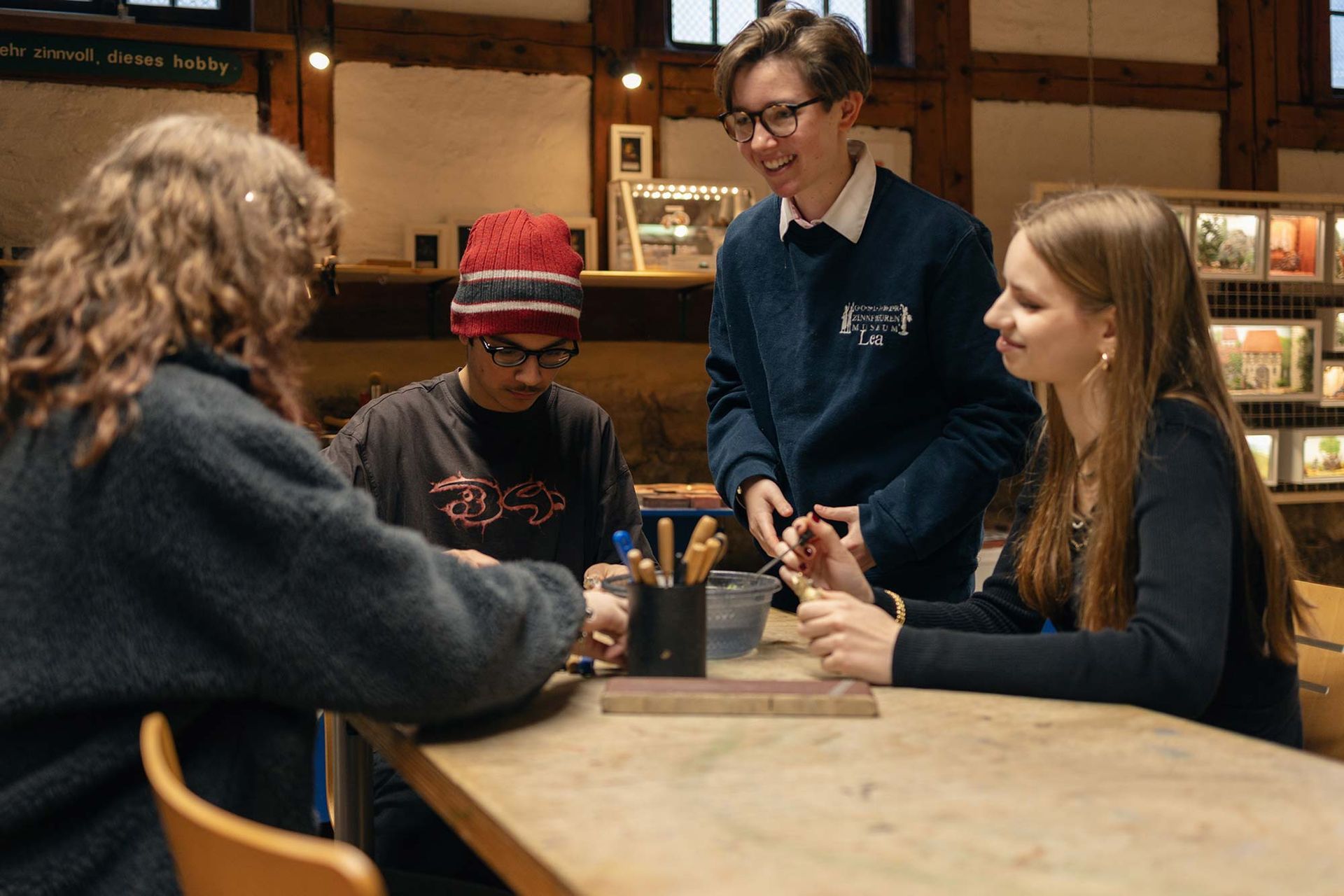Eine Gruppe junger Leute sitzt an einem Tisch in einer Bibliothek.