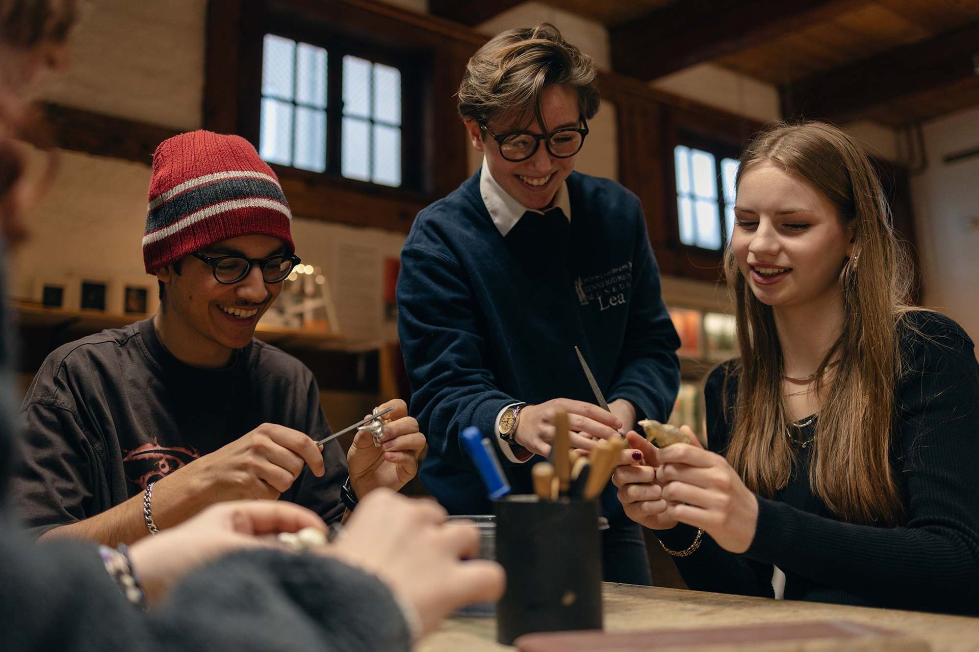 Eine Gruppe junger Leute sitzt um einen Tisch herum und arbeitet an einem Projekt.