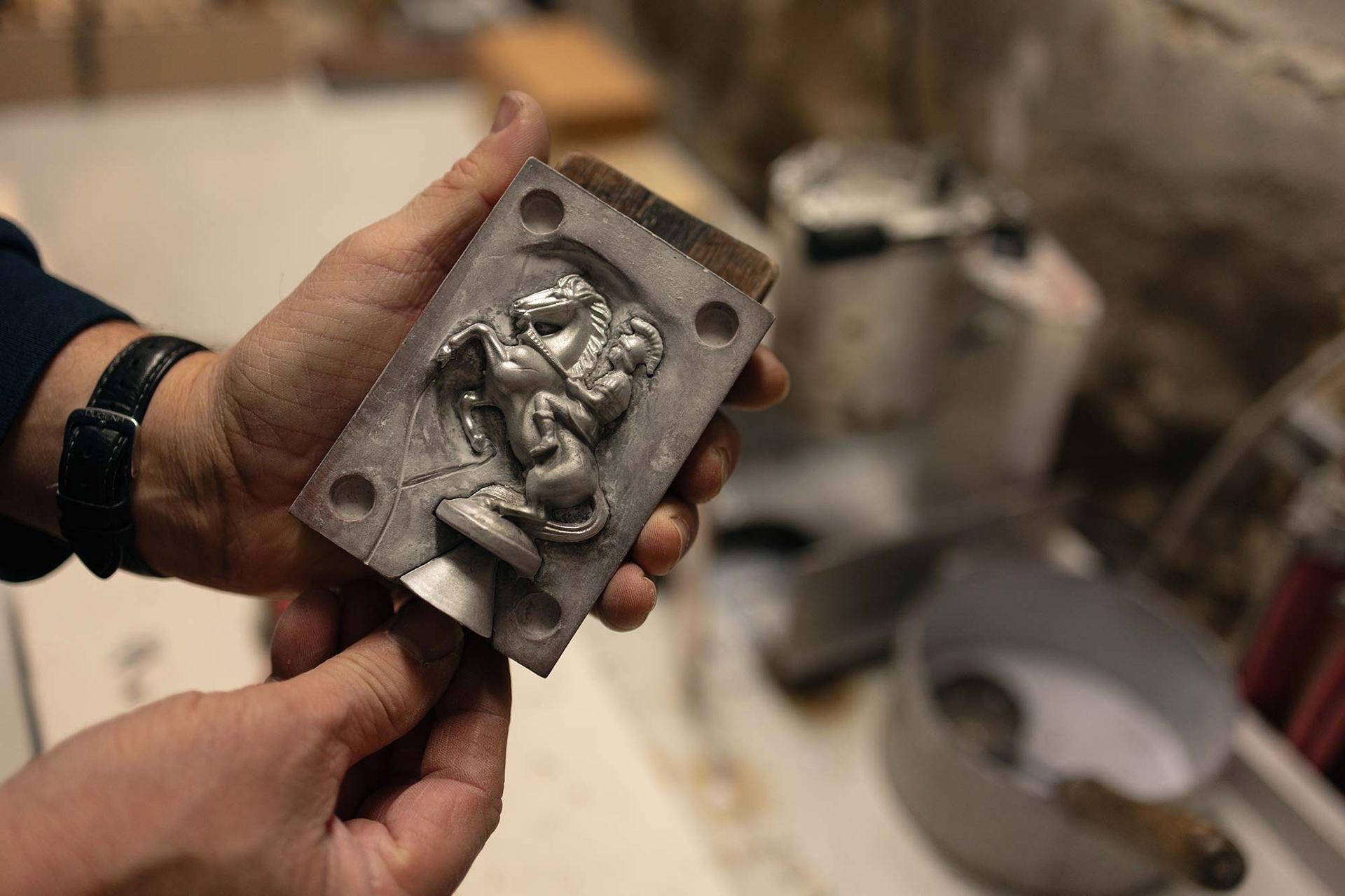 Eine Person hält ein Stück Metall in den Händen.