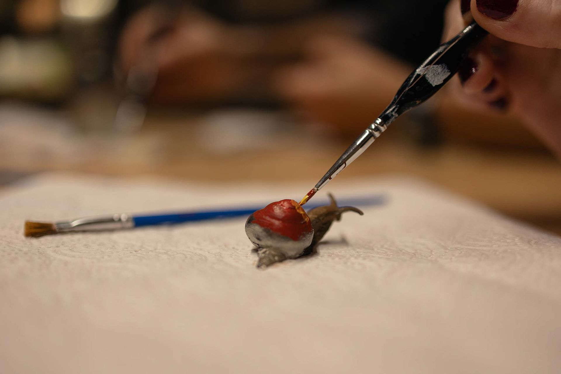 Eine Person malt mit einem Pinsel eine Schnecke auf ein Blatt Papier.