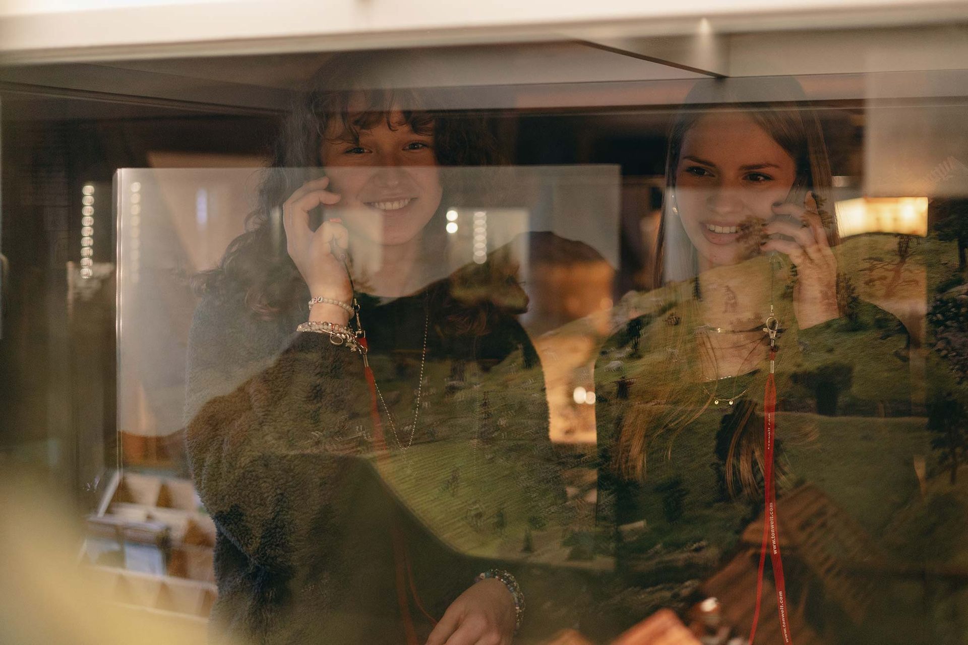 Zwei Frauen telefonieren und schauen dabei aus dem Fenster.