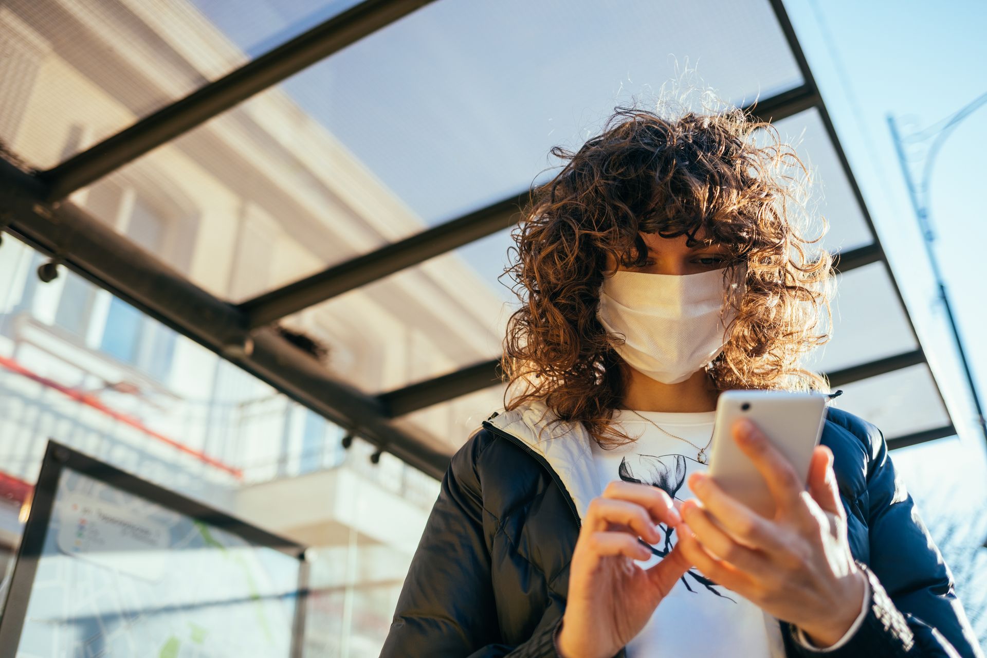Une personne portant un masque regarde son téléphone.