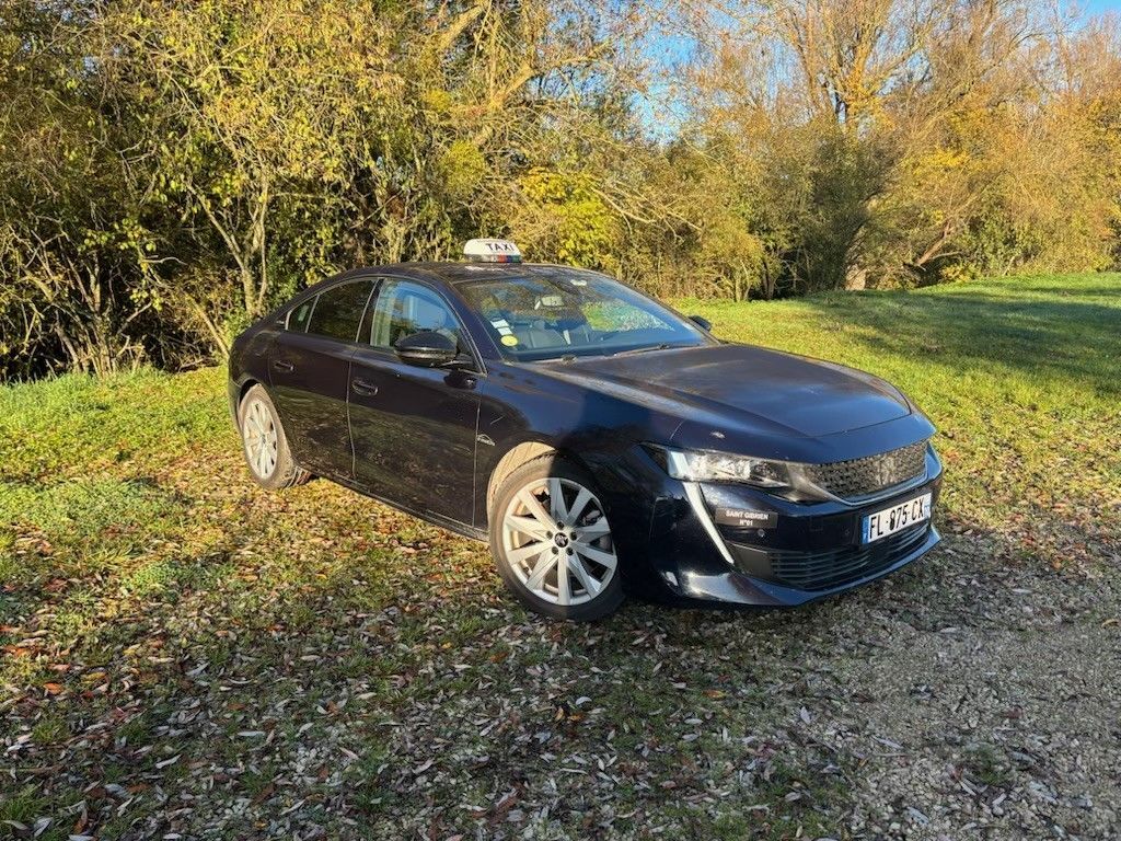 Taxi bleu foncé garé sur un terrain herbeux.