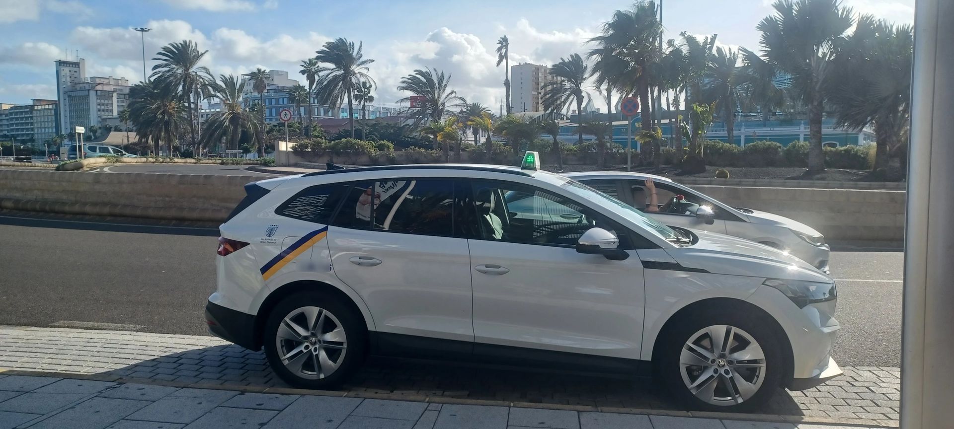 Dos coches blancos están aparcados uno al lado del otro al costado de la carretera.