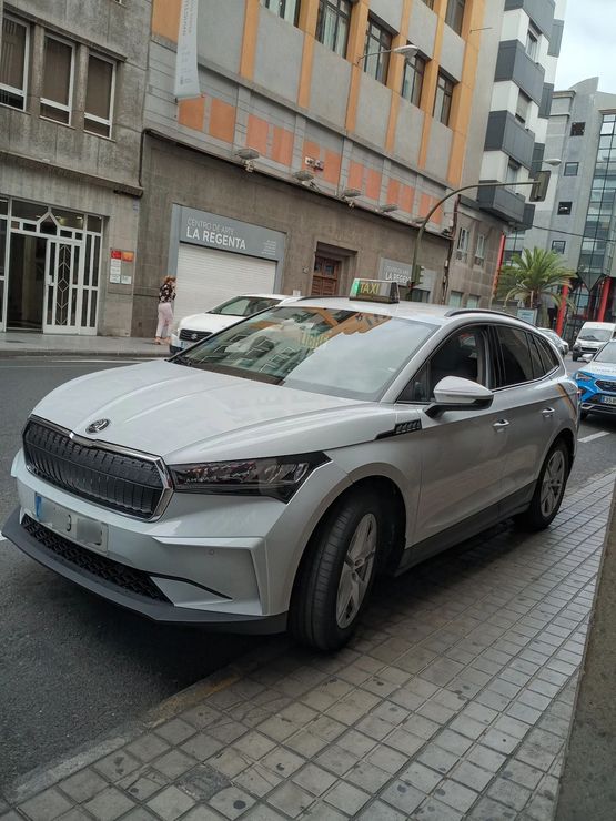 Un coche plateado está aparcado al costado de la carretera frente a un edificio.