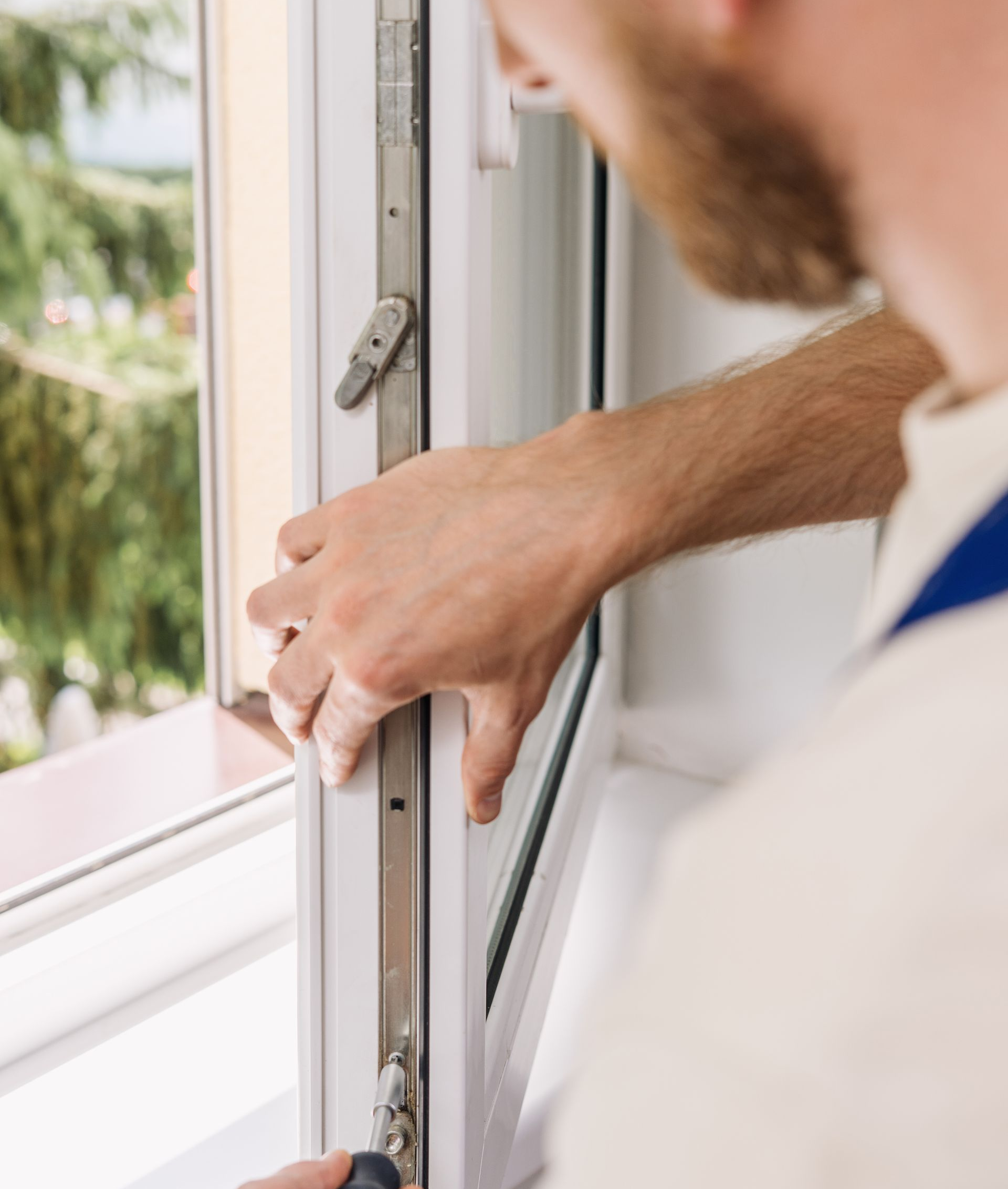 Un homme installe une fenêtre. Il utilise un outil sur le cadre.