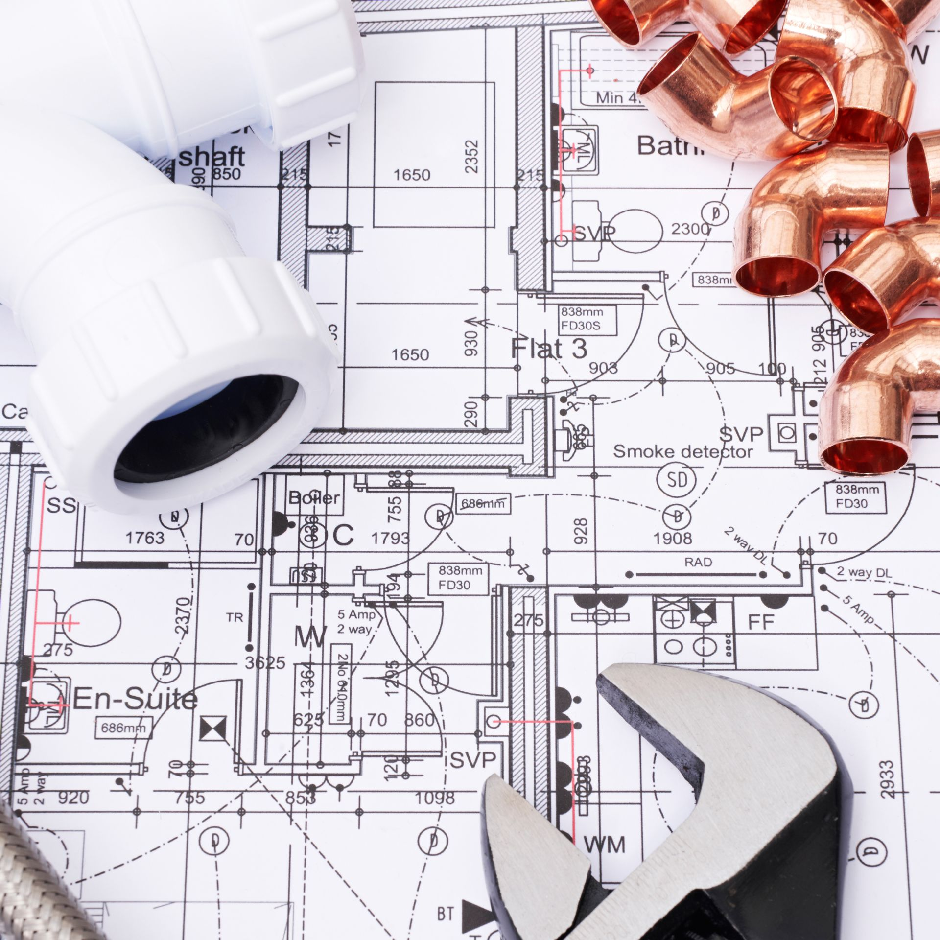 Outils et tuyaux de plomberie posés sur un plan.