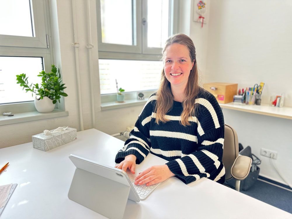 Ein Mann in einem schwarzen Poloshirt steht vor einer Wand mit Gemälden.