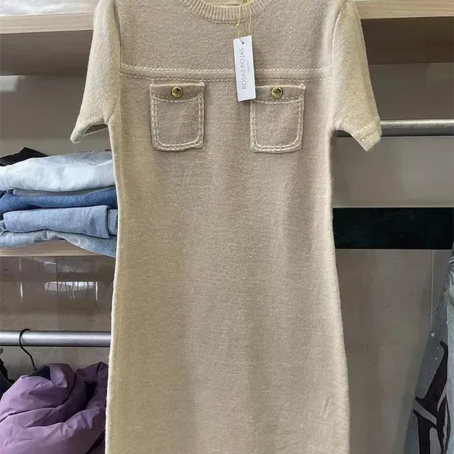 Un vestido beige con bolsillos está colgado en un perchero en un armario.