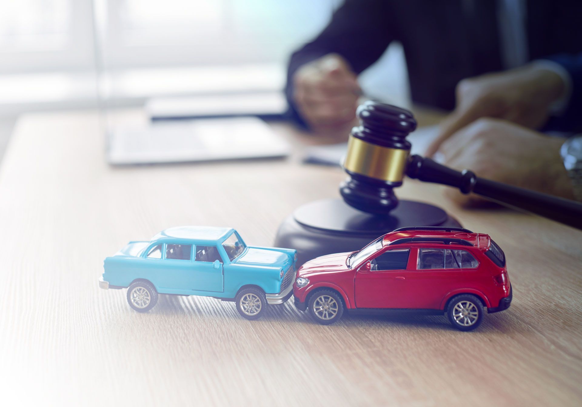 Deux miniatures de voitures se percutant sur le bureau d'un cabinet d'avocats