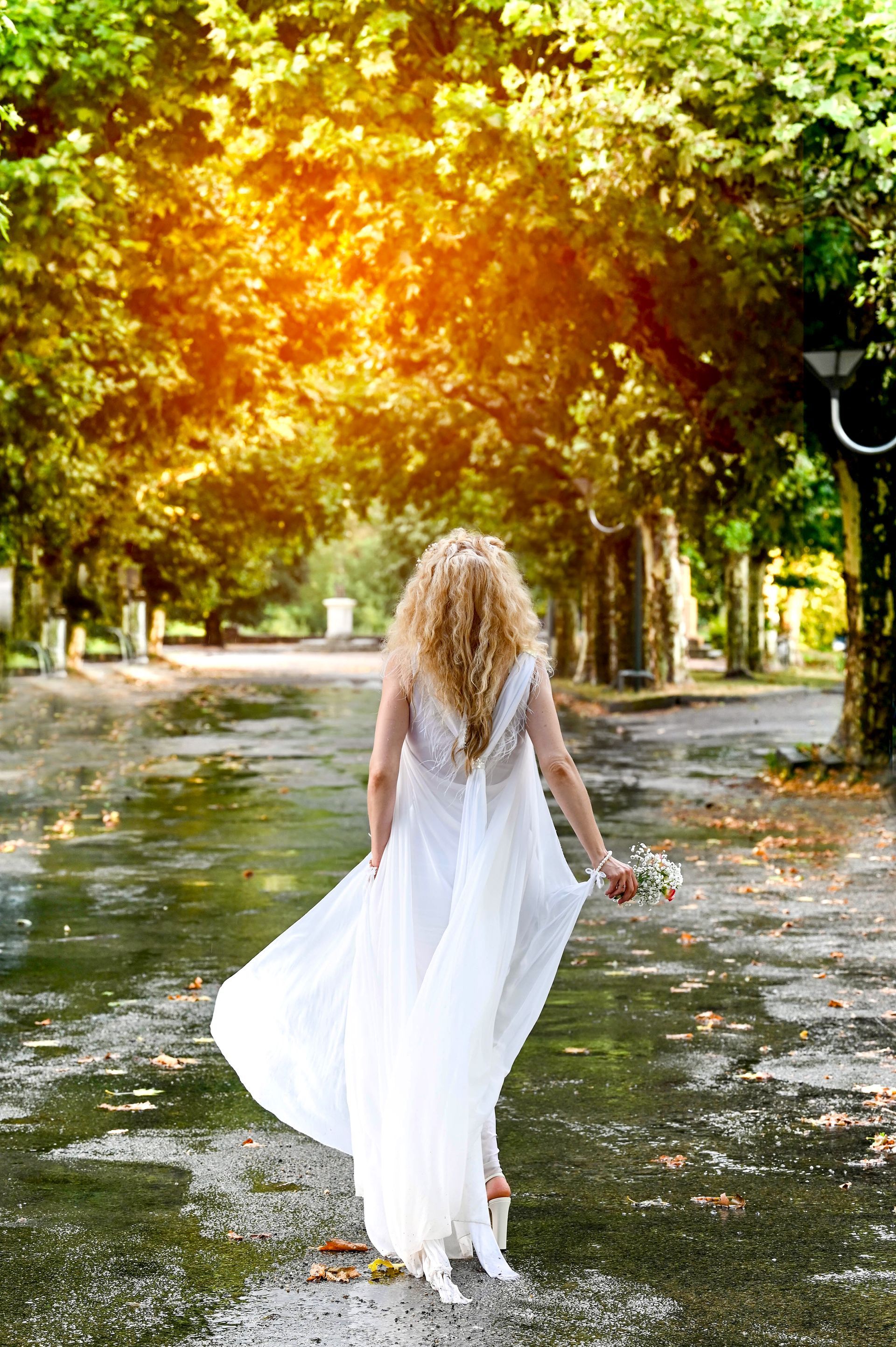 Mariée blonde prise de dos, vêtements dans le vent