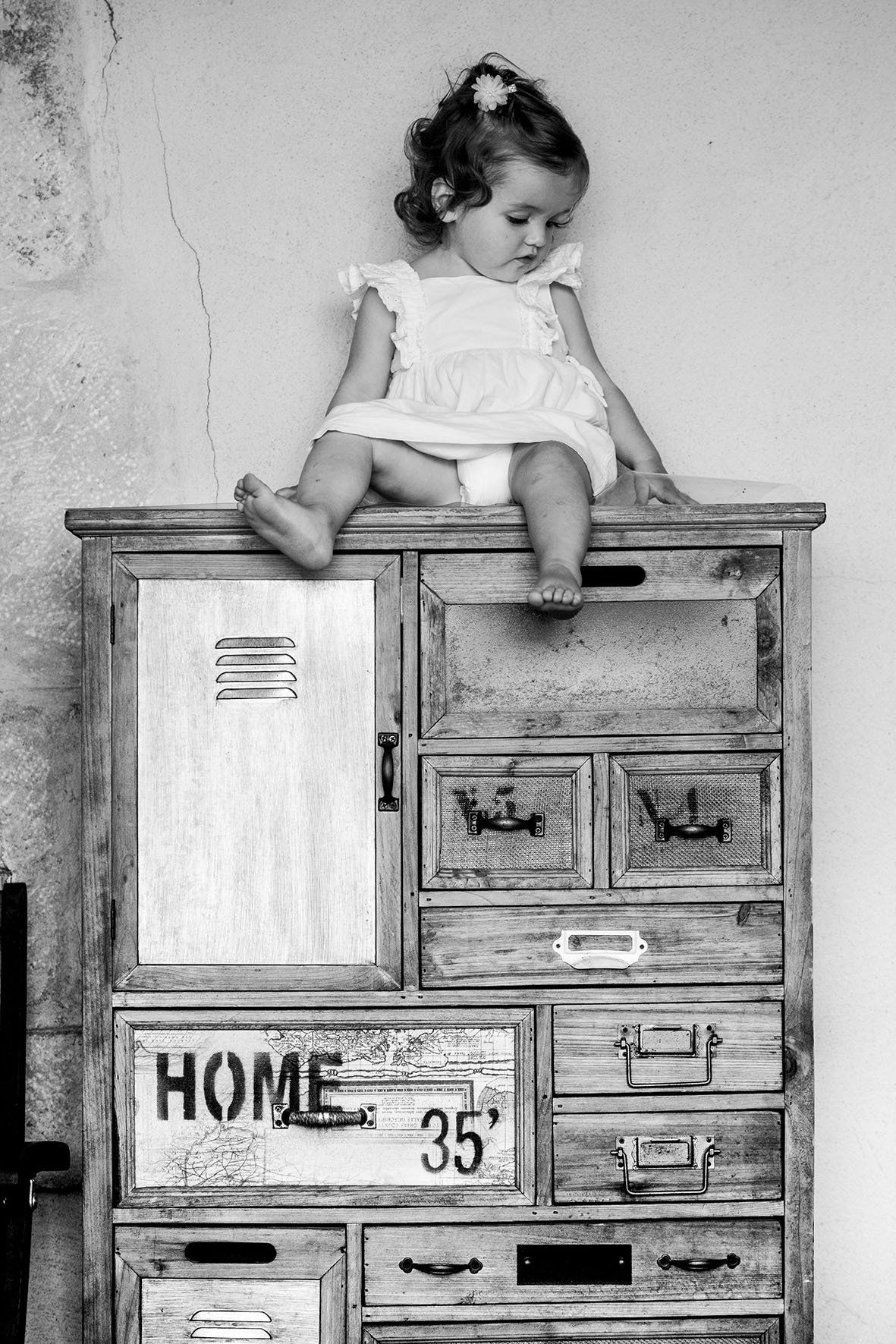 Photo d'un jeune enfant assis sur une commode en noir et blanc
