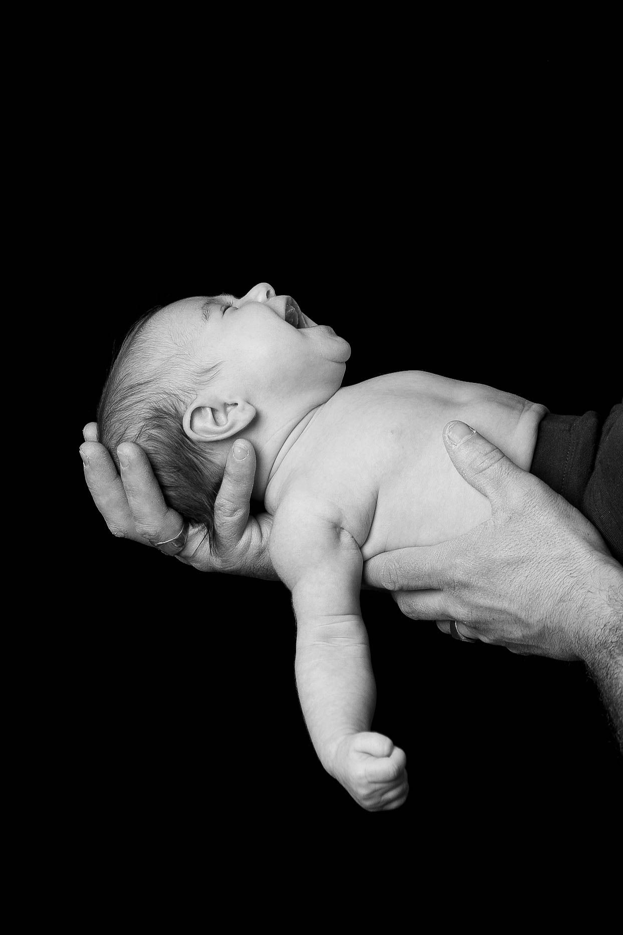 Nourrisson allongé tenu par un adulte en noir et blanc