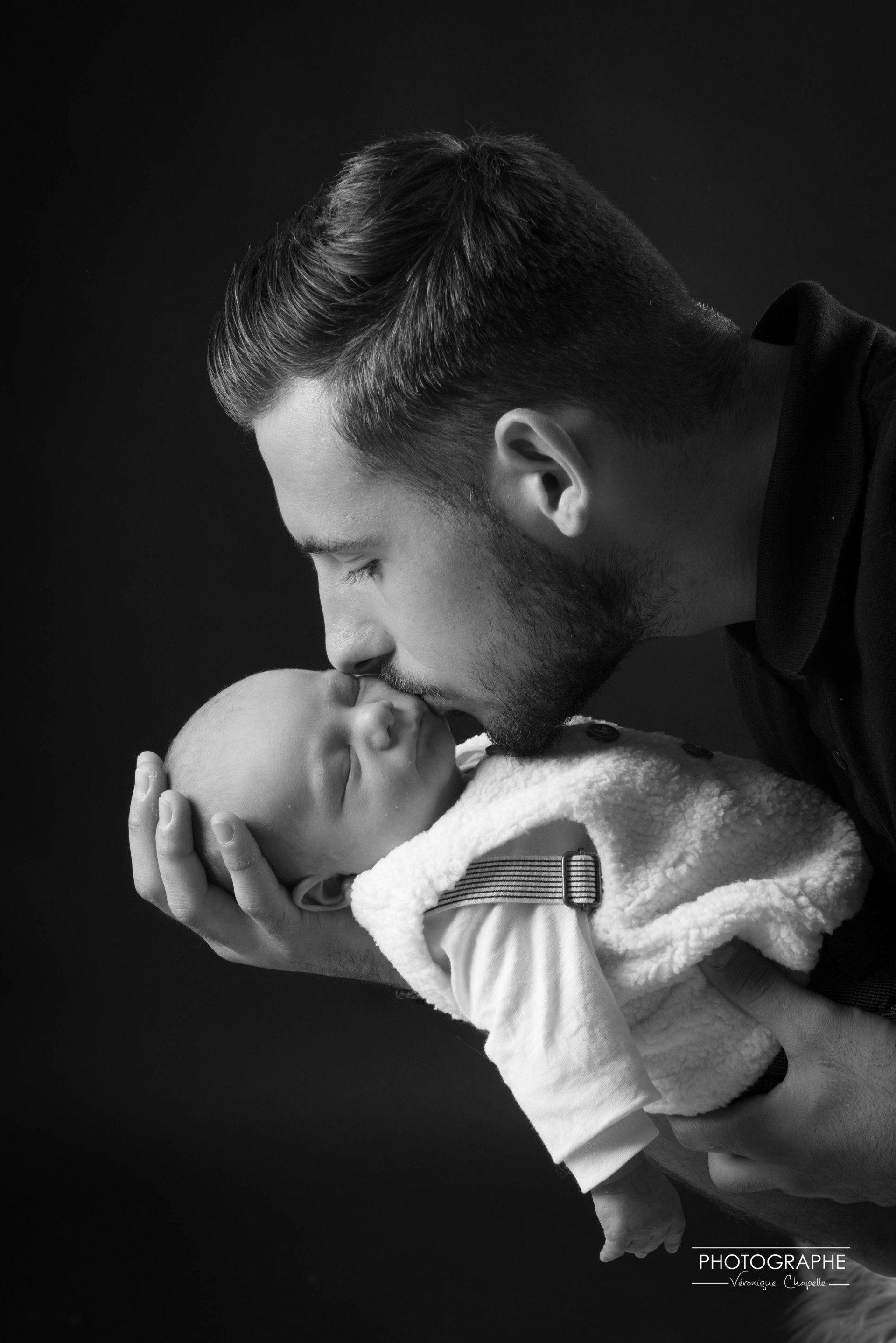 Portrait d'un père embrassant la joue de son nourrisson en noir et blanc