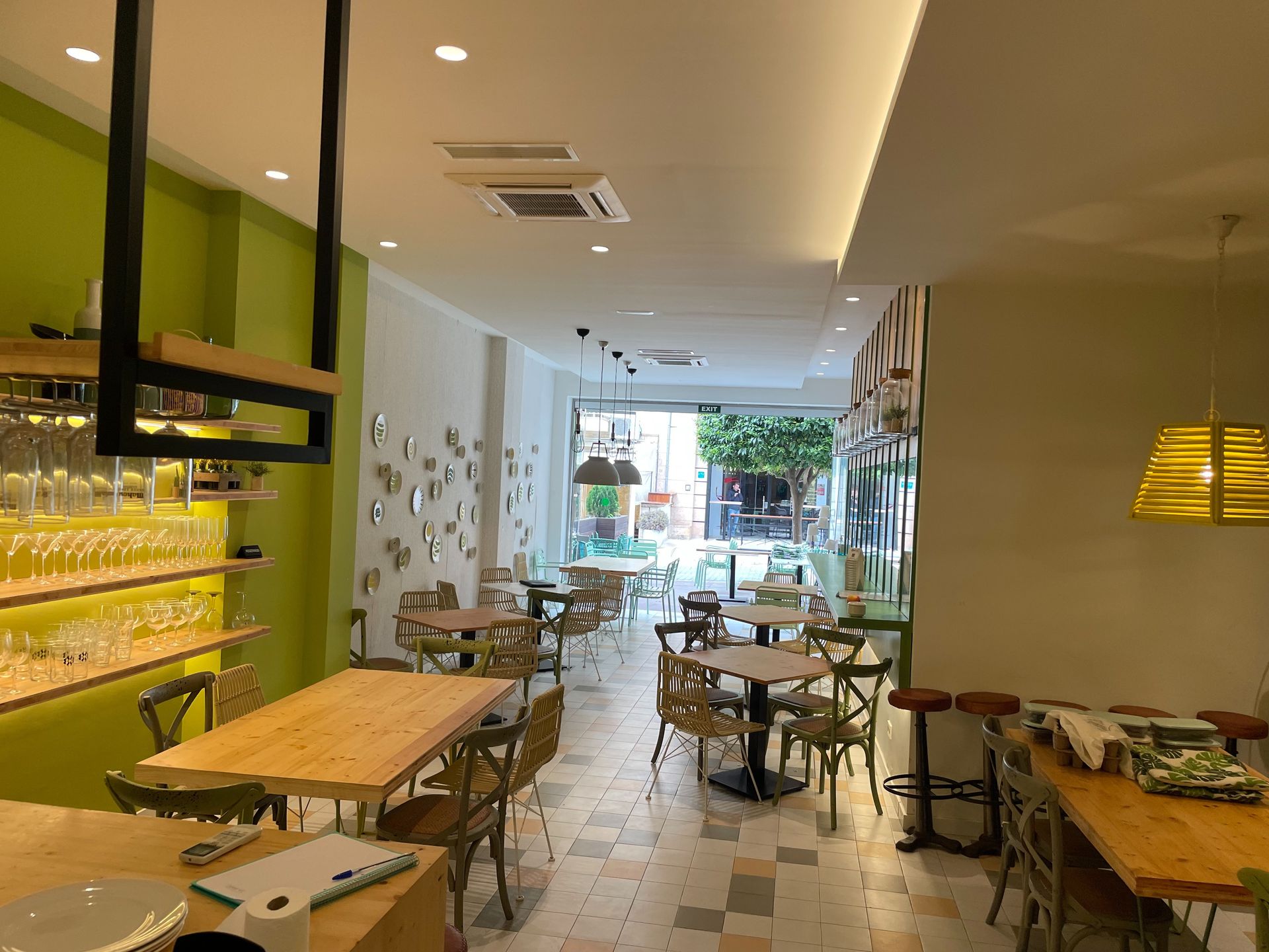 Un restaurante con mesas y sillas de madera y una pared verde.