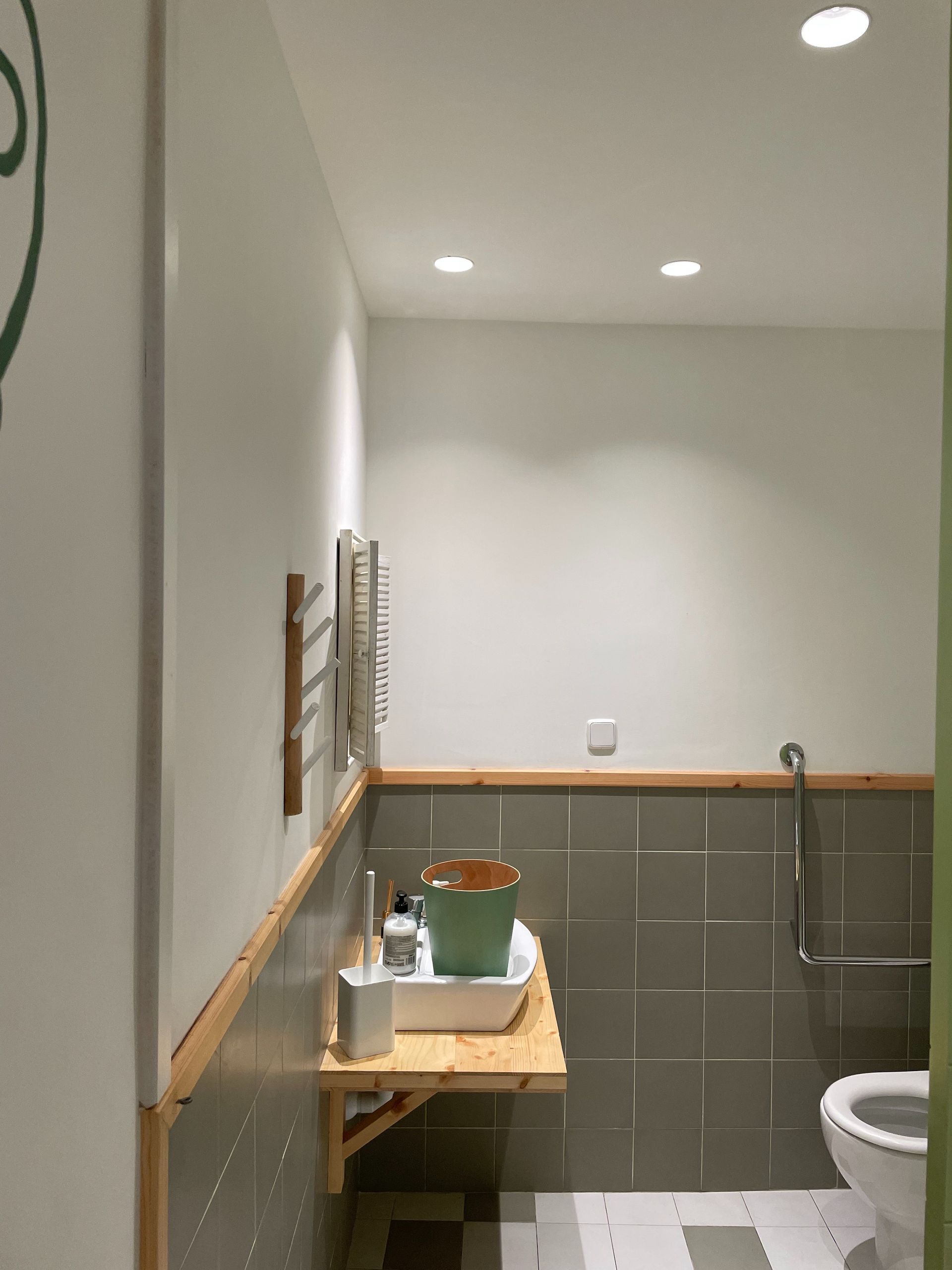 Un baño con un cubo en un estante y un inodoro.