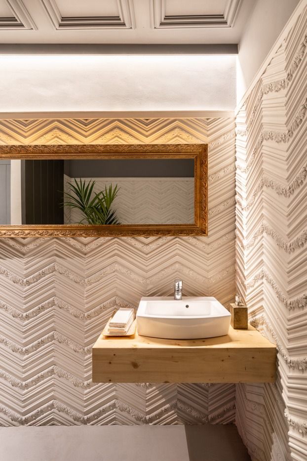 Un baño con lavabo, espejo y encimera de madera.