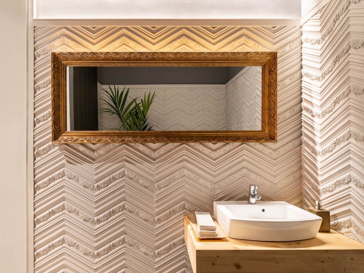 Un baño con lavabo y un gran espejo en la pared.