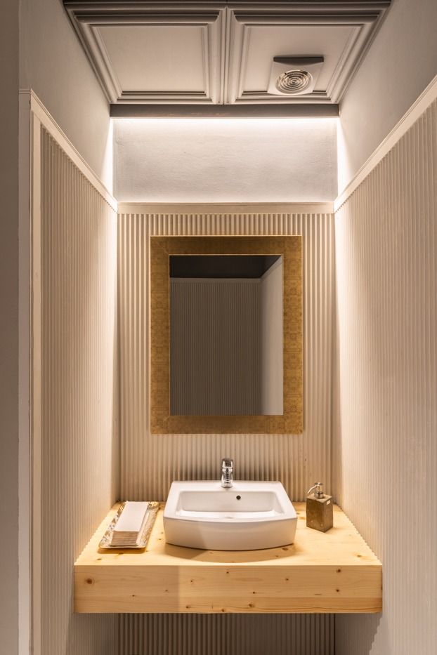 Un baño con lavabo, espejo y encimera de madera.