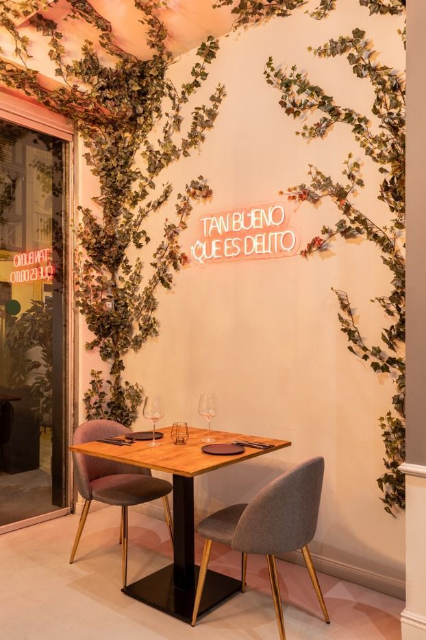 Un restaurante con una mesa y sillas frente a una pared con hiedra creciendo en ella.