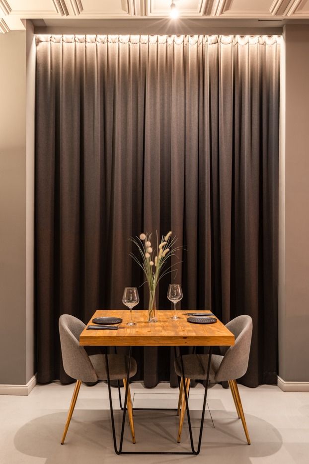 Un comedor con una mesa y sillas frente a una cortina.