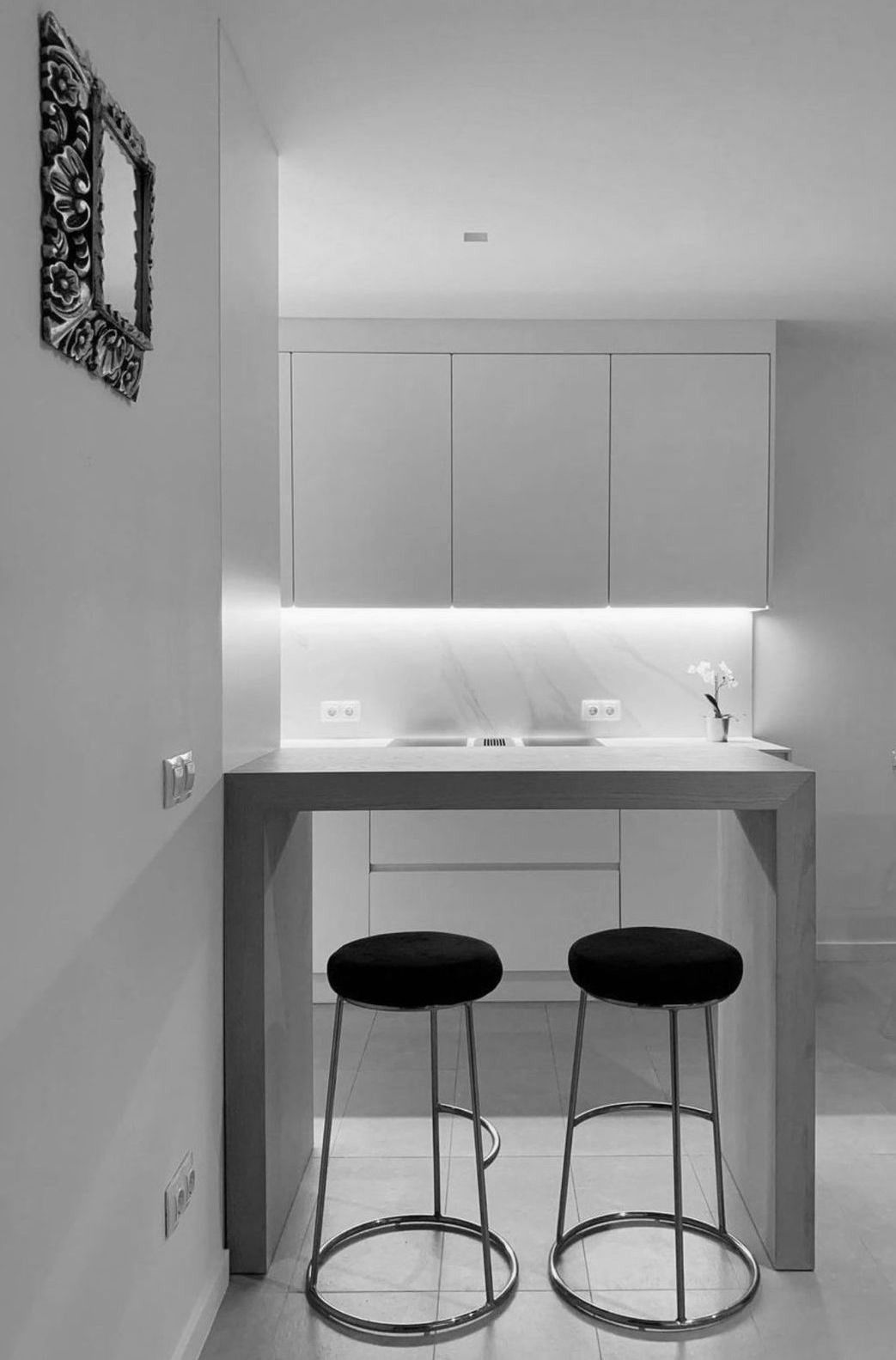 Una fotografía en blanco y negro de una cocina con dos taburetes de bar.