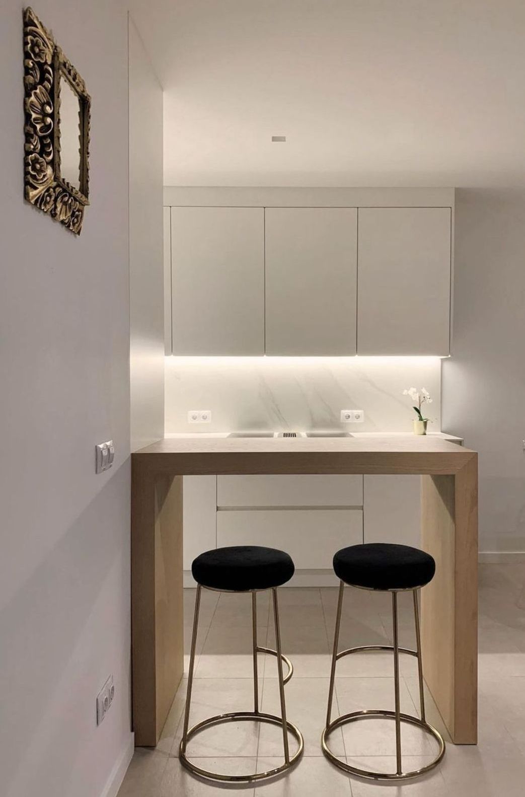 Una cocina con dos taburetes de bar y un espejo en la pared.