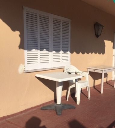 Un patio con una mesa y sillas frente a una ventana con contraventanas.