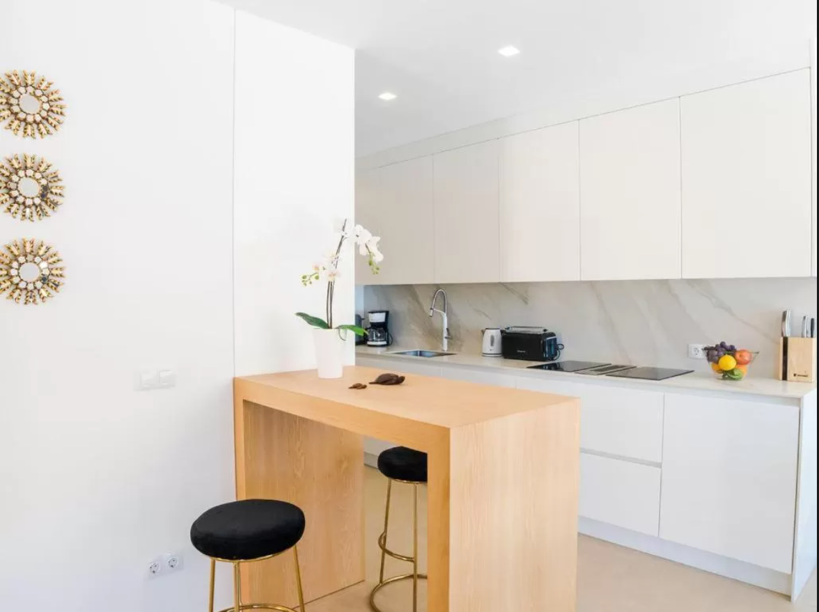 Una cocina con una mesa de madera y dos taburetes.