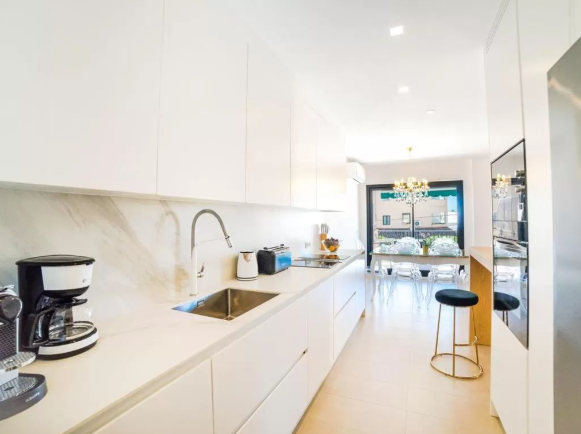 Una cocina con gabinetes blancos y un fregadero de acero inoxidable.
