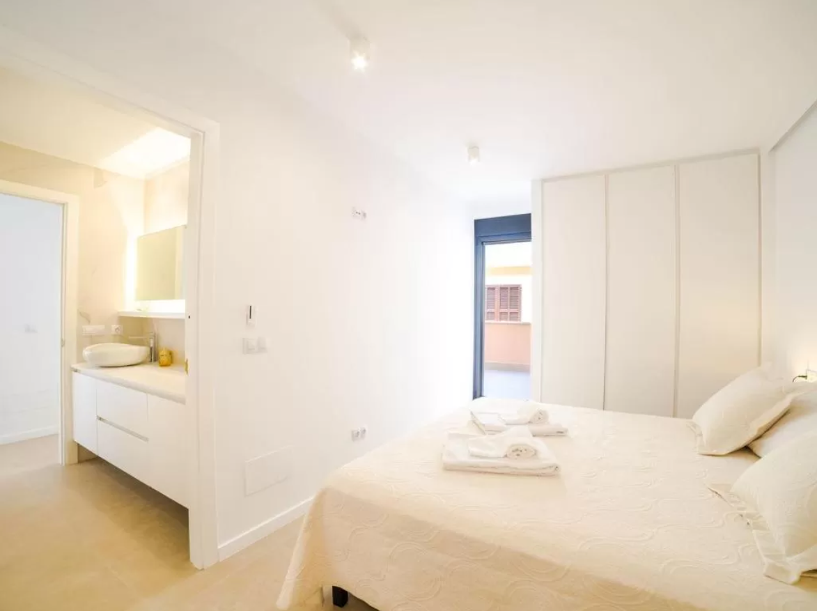 Un dormitorio con una cama y un baño al fondo.