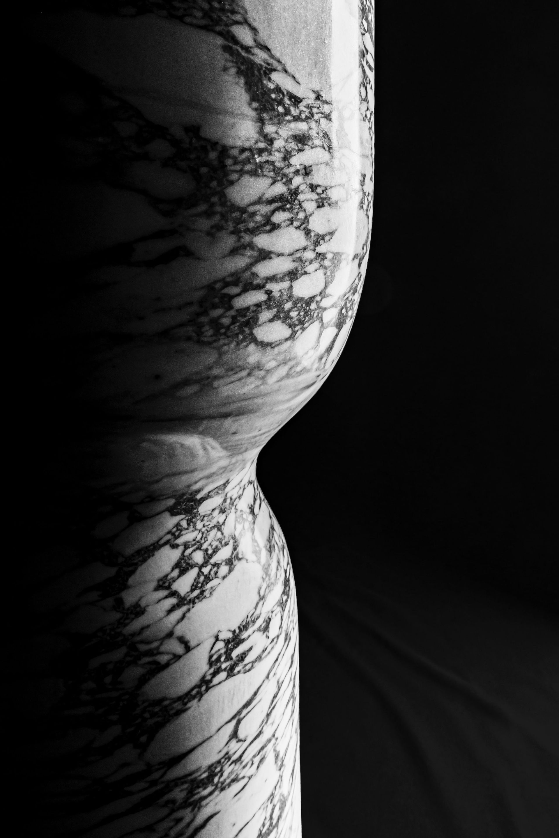 Una fotografía en blanco y negro de una escultura de mármol sobre un fondo negro.