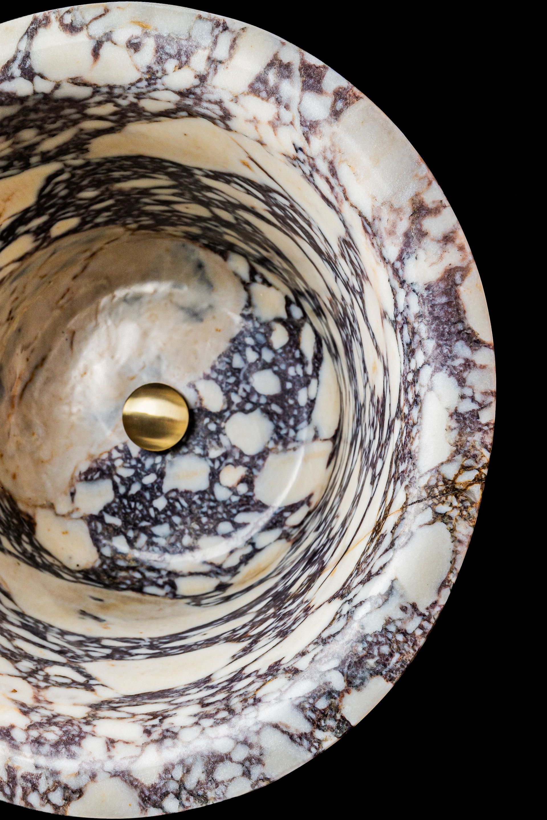 Un primer plano de un lavabo de mármol con un grifo dorado.