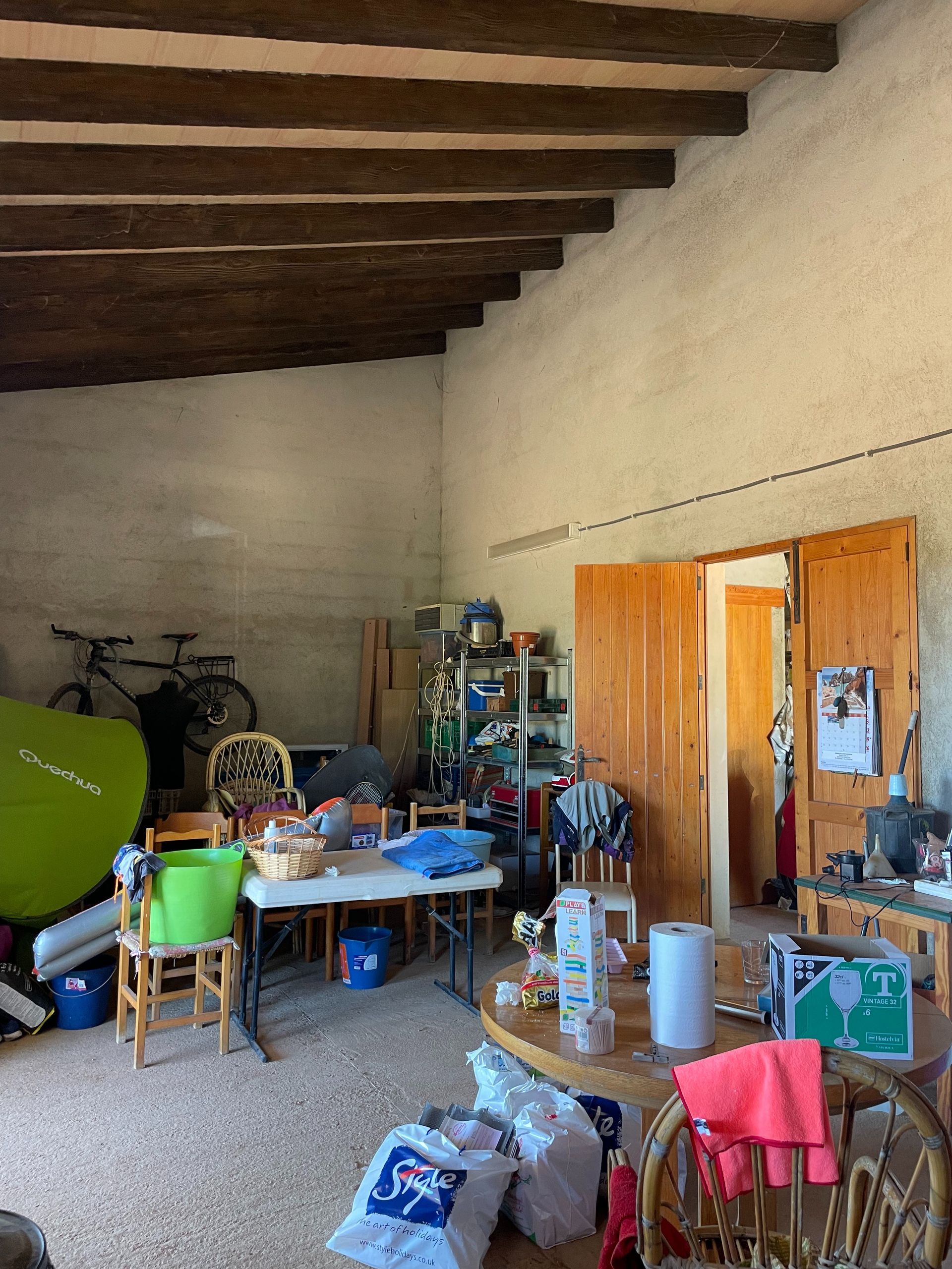 Una habitación con muchos objetos en el suelo y una mesa y sillas.