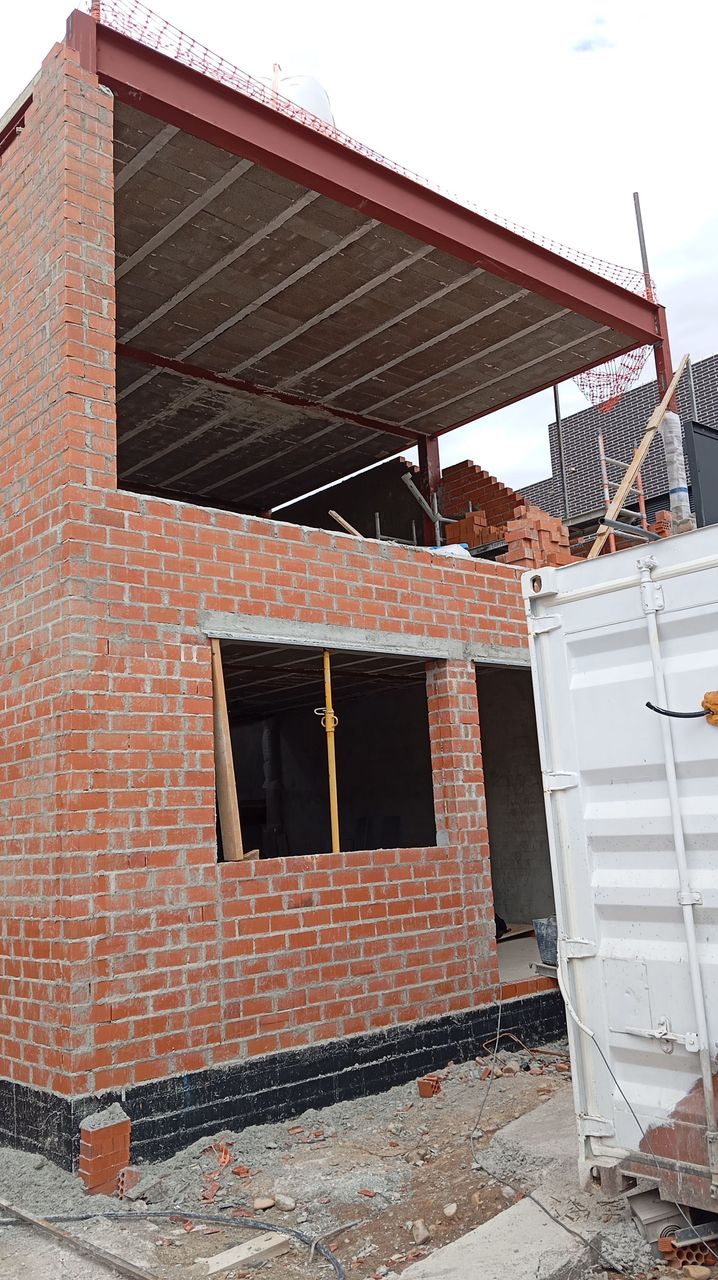 Se está construyendo un edificio de ladrillos al lado de un contenedor de envío blanco.