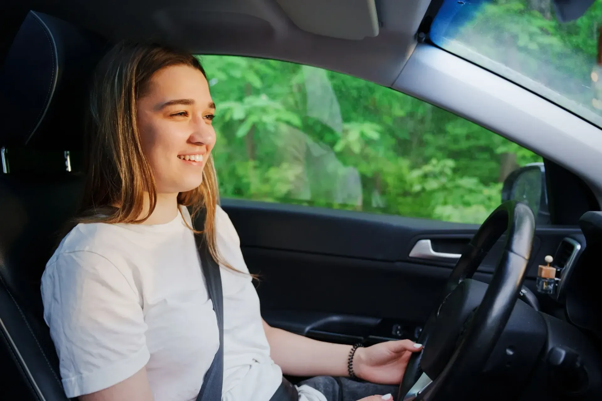 Mujer sonriendo en un coche, conduciendo.