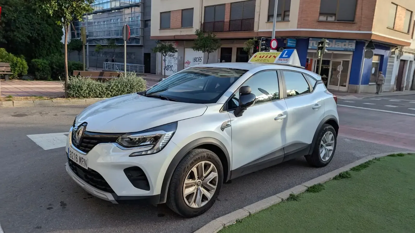 Semáforo en rojo y señal azul de “siga recto” en el tronco de un árbol.
