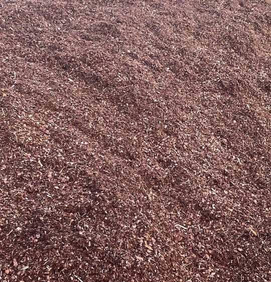 Haufen aus rotbraunem, zerkleinertem Mulch.