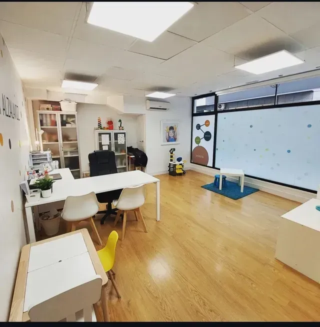 Espacio de oficina moderno y luminoso con muebles blancos, suelo de madera y calcomanías decorativas para la pared.