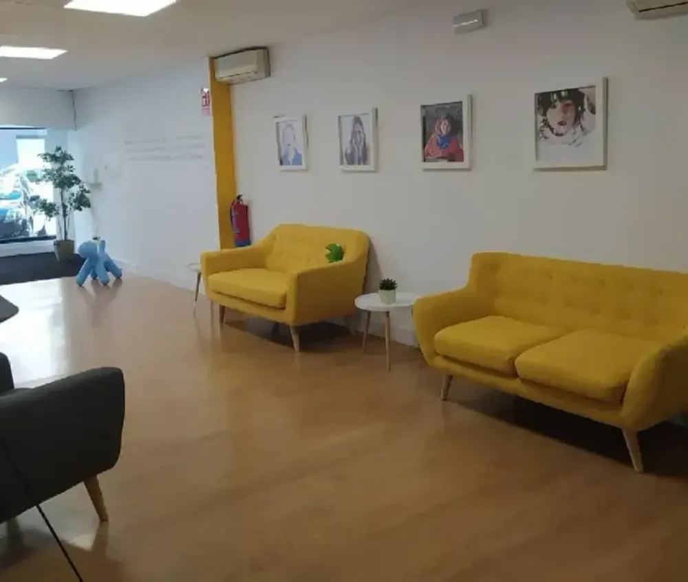 Una sala de espera con sofás amarillos, arte y pisos de madera.