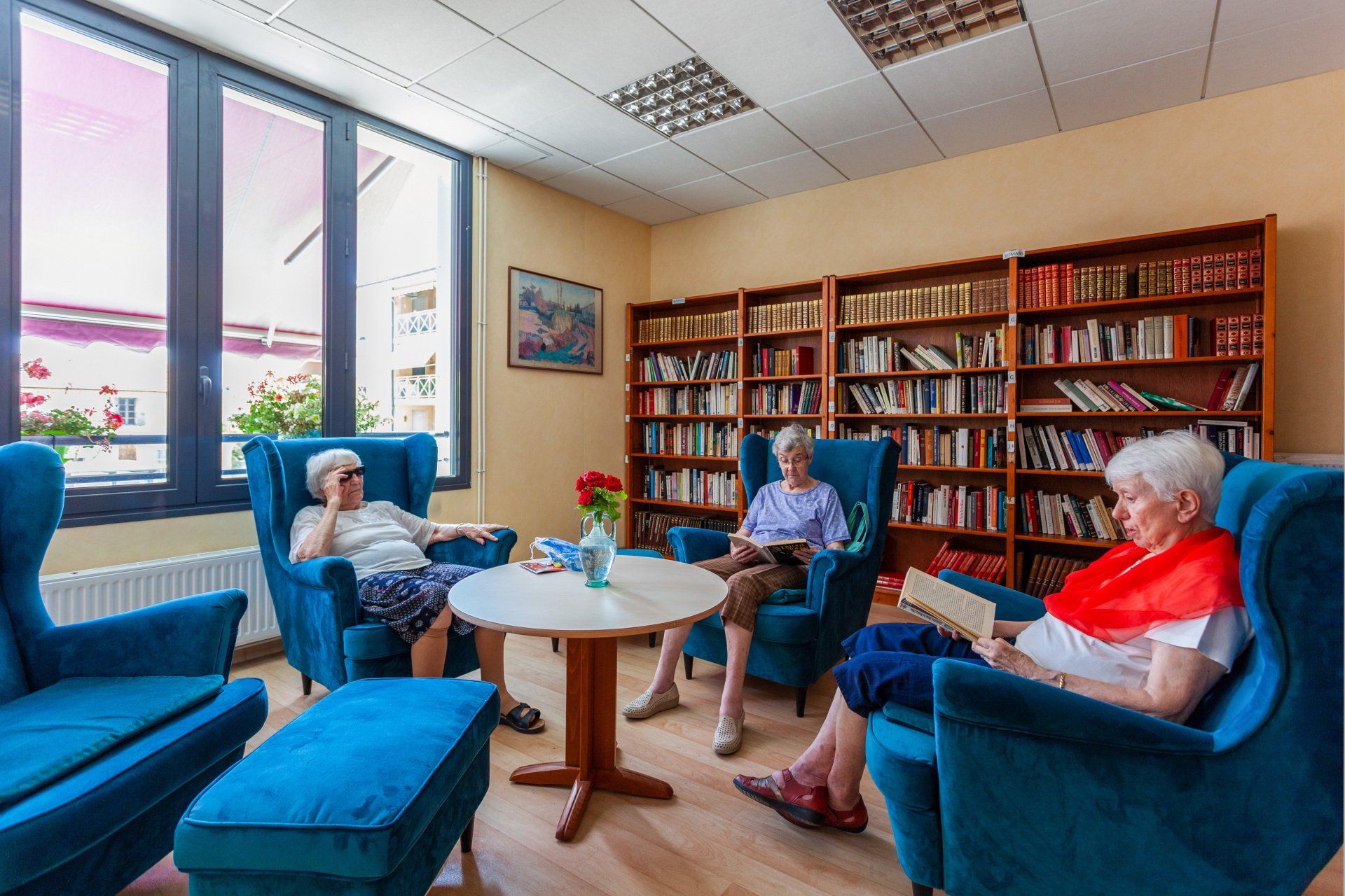 Personnes âgées dans des fauteuils en train de lire dans une pièce avec des bibliothèques et des livres