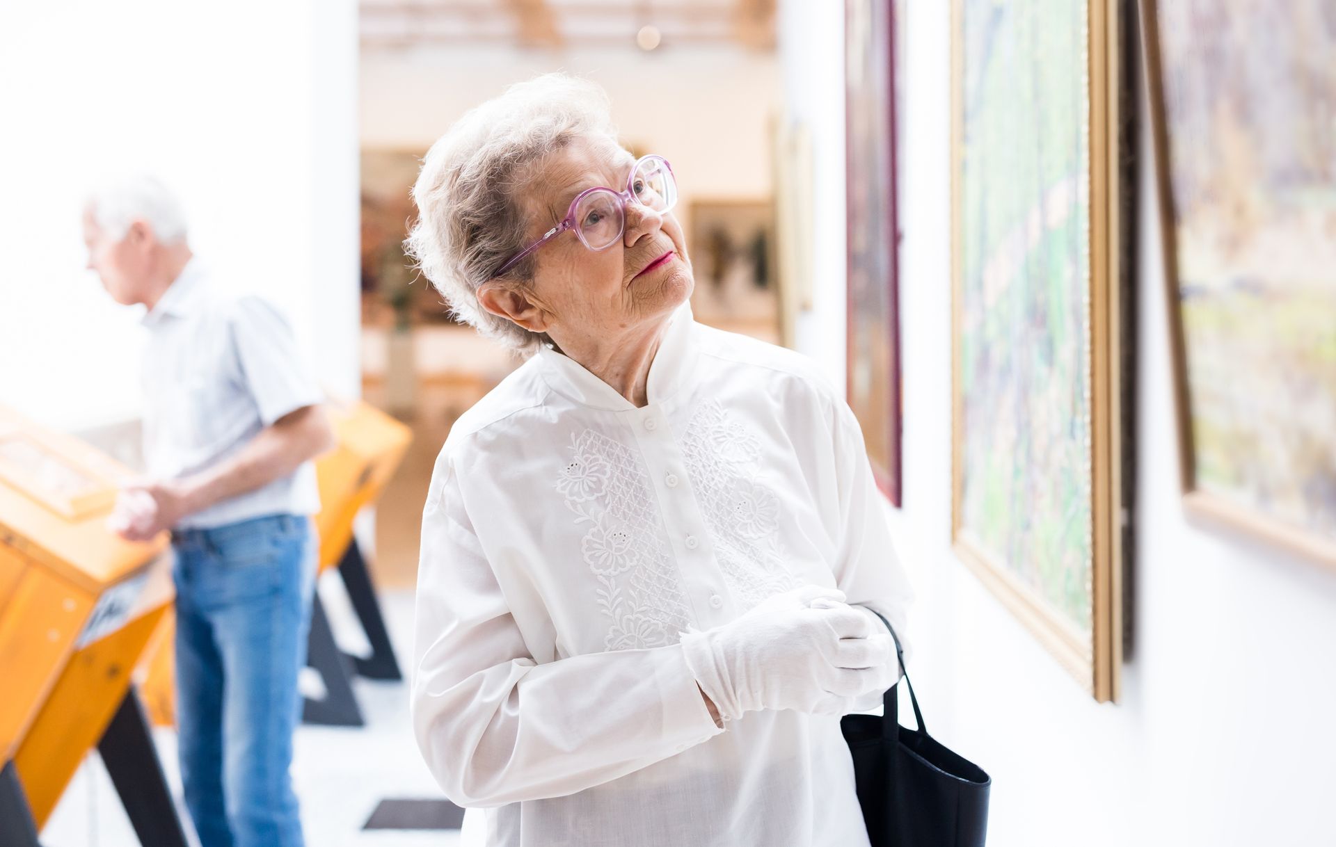 Dame âgée regardant une toile dans un musée