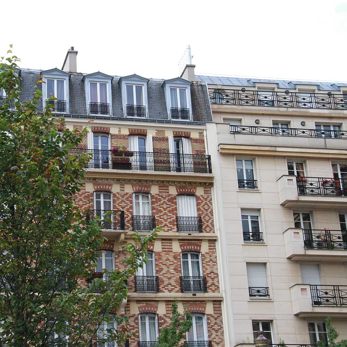 Bâtiments parisiens aux façades en briques et crème, avec balcons et lucarnes.