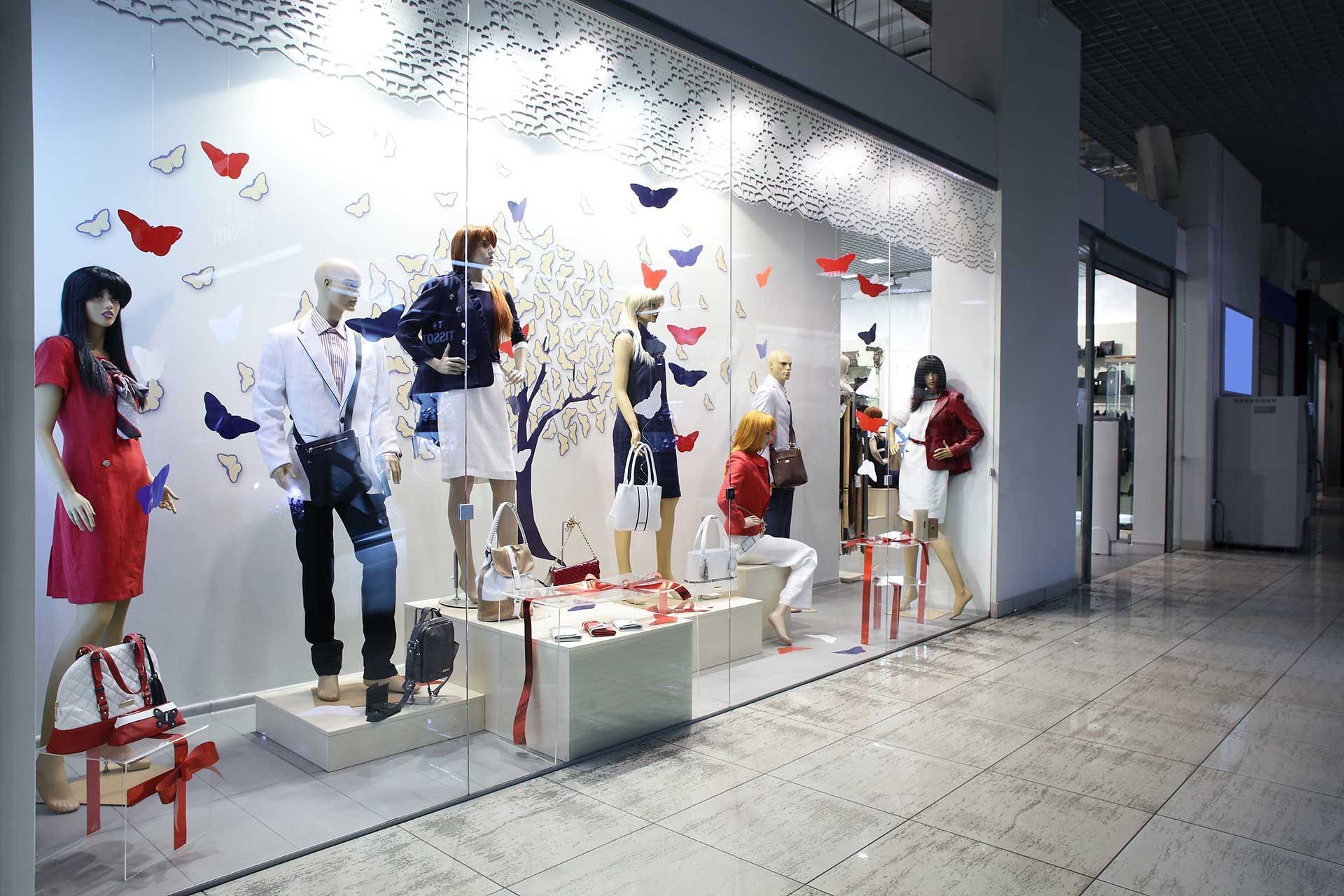 Vitrine avec mannequins portant des vêtements à la mode, accents de papillons.