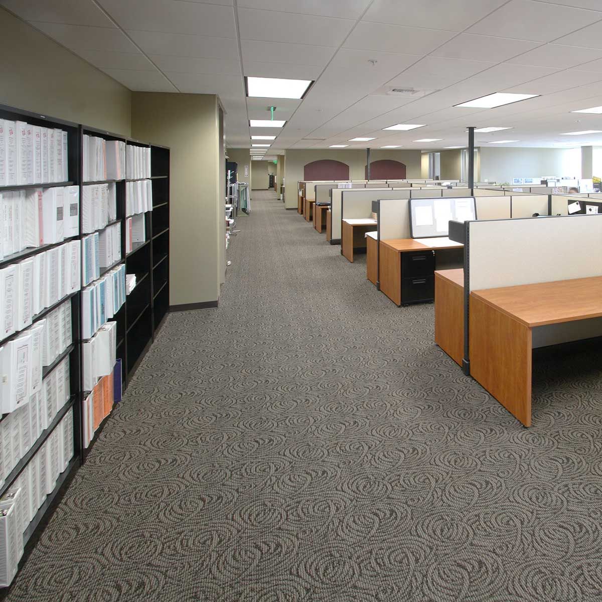 Un intérieur de bureau avec des rangées de bureaux et d'étagères le long du mur.