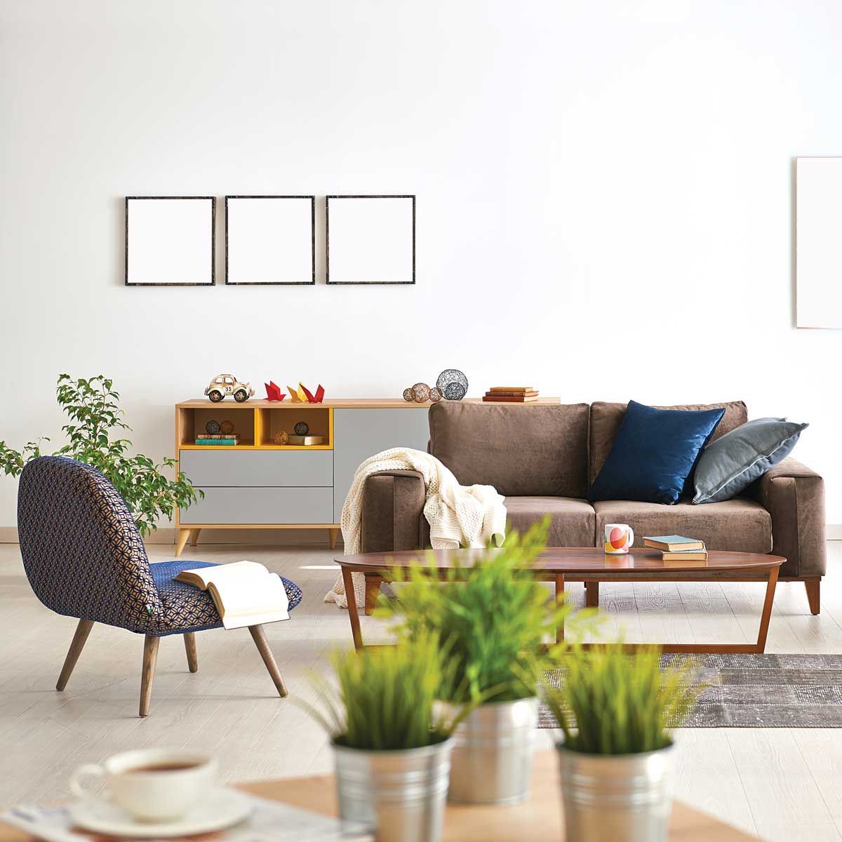 Salon avec canapé marron, fauteuil d'appoint, table basse en bois, plantes en pot et décoration murale.