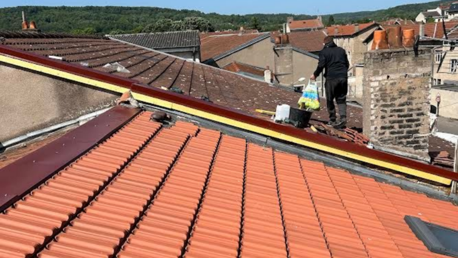 Une camionnette blanche équipée d'un bras de levage pointant vers un bâtiment. La camionnette arbore un marquage vert et noir.